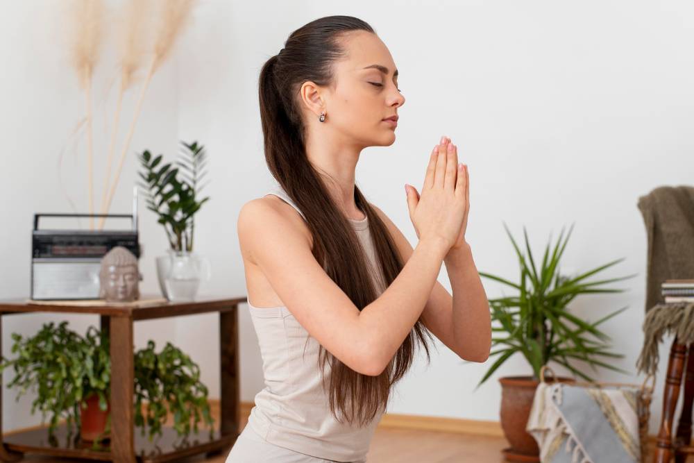 A young woman practicing mindfulness and breathing techniques at home, symbolizing Somatic Therapy in Denver for emotional grounding and mental clarity.